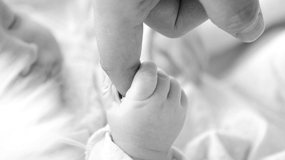 Ein Baby hält den Finger eines Erwachsenen fest