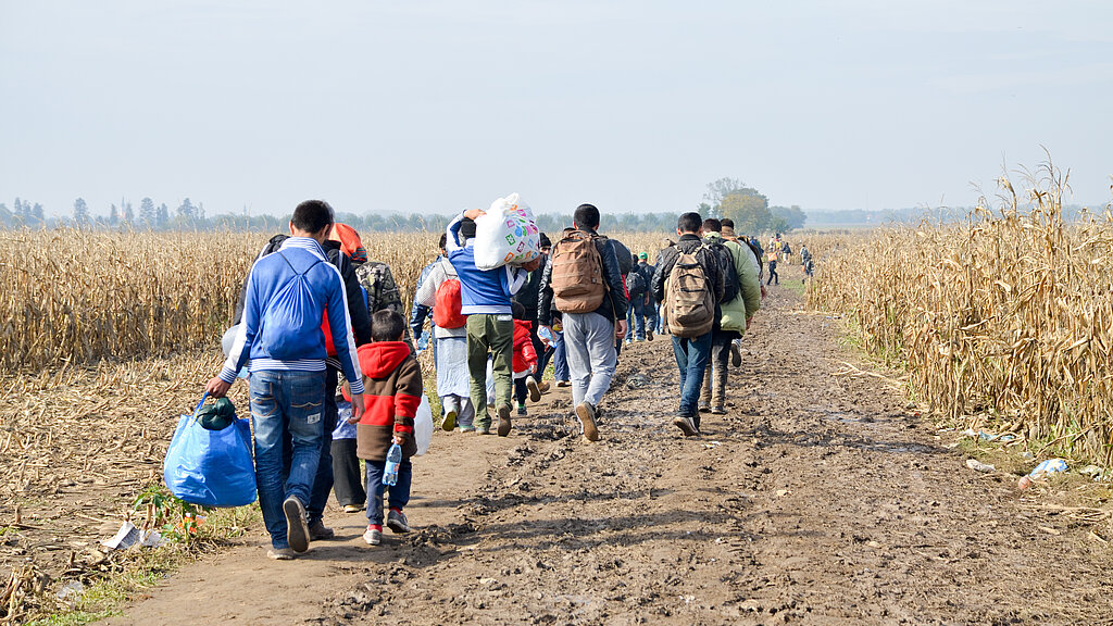Wanderung von Flüchtlingen über einen Feldweg